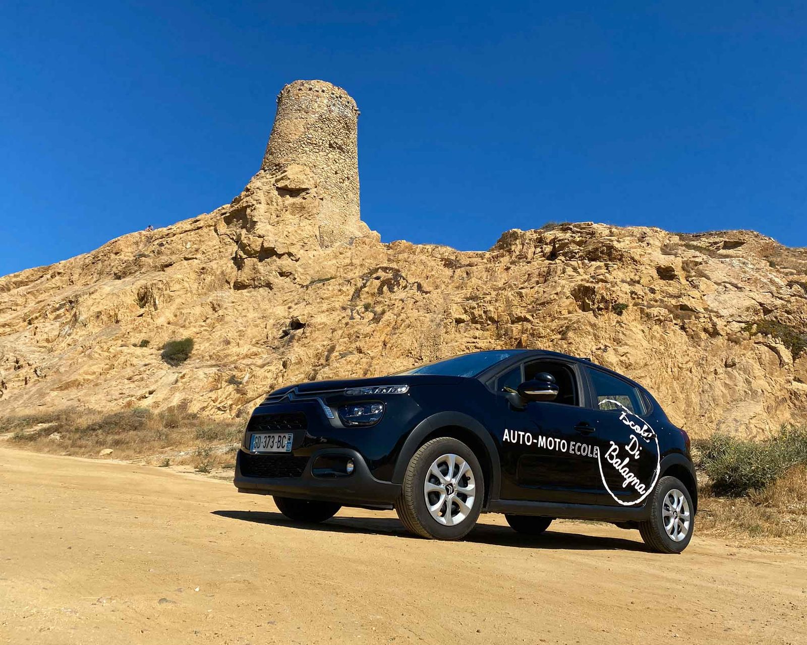 Une voiture de l'auto-école Scola Di Balagna au pied de la tour génoise de l'Île-Rousse